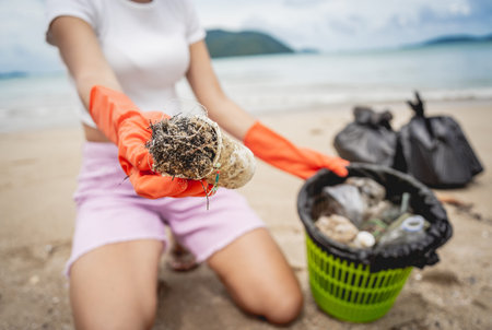 A female ecologist volunteer cleans the beach on the seashore from plastic and other waste