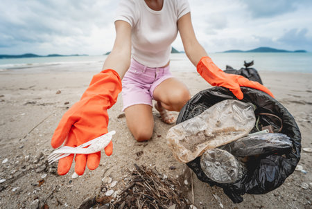 A female ecologist volunteer cleans the beach on the seashore from plastic and other waste