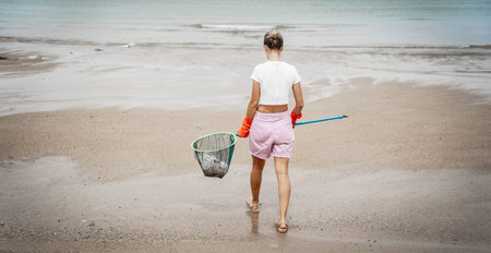A female ecologist volunteer cleans the beach on the seashore from plastic and other wasteの写真素材