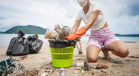 A female ecologist volunteer cleans the beach on the seashore from plastic and other wasteの写真素材