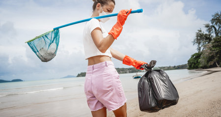 A female ecologist volunteer cleans the beach on the seashore from plastic and other wasteの写真素材