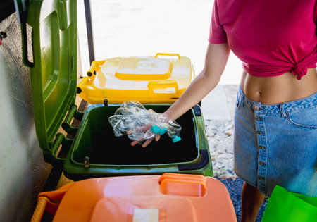 A young beautiful girl throws sorted garbage into special binsの写真素材