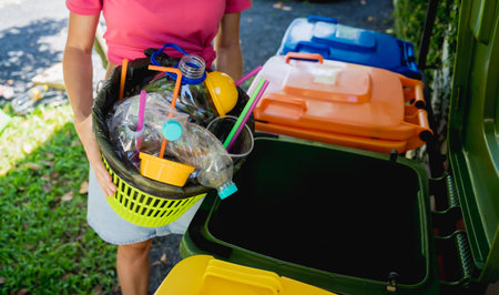 A young beautiful girl throws sorted garbage into special binsの写真素材