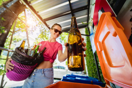 A young beautiful girl throws sorted garbage into special binsの写真素材