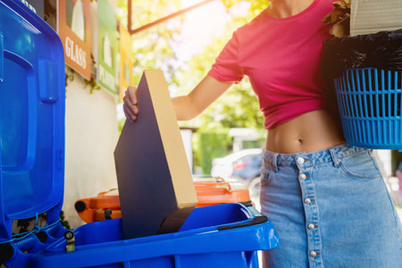 A young beautiful girl throws sorted garbage into special binsの写真素材
