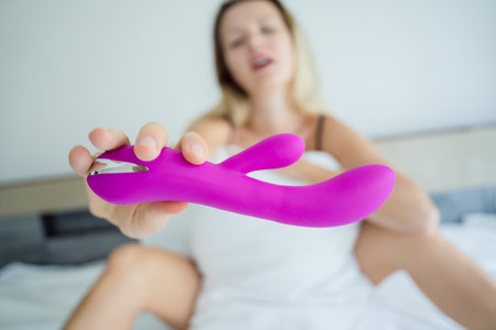 Young sexy woman in the bed holding in her hands a sex toy for adultsの写真素材