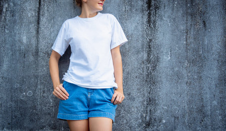 Female model wearing white blank t-shirt on the background of an gray scratched wall.