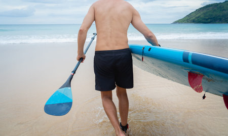 Young man with a board at quiet sunset sea