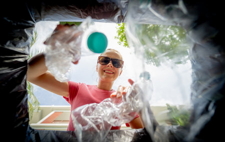 A young beautiful girl throws sorted garbage into special binsの写真素材