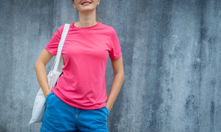 Female model wearing pink blank t-shirt on the background of an gray scratched wall.