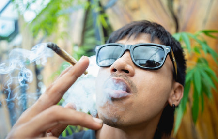 Young man smoking cigarettes with medical marijuanaの写真素材