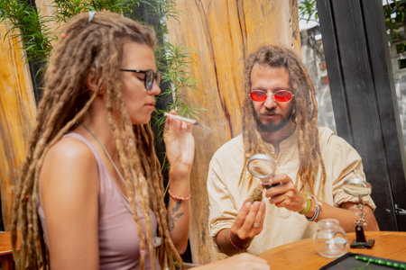 Hippie style couple smoking cigarettes with medical marijuanaの写真素材