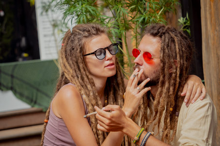Hippie style couple smoking cigarettes with medical marijuana