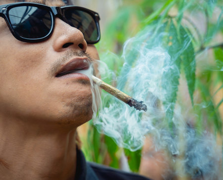 Young man smoking cigarettes with medical marijuanaの写真素材