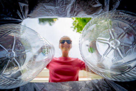 A young beautiful girl throws sorted garbage into special bins
