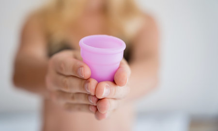 Young beautiful woman at home holding a menstrual cup in her handsの写真素材