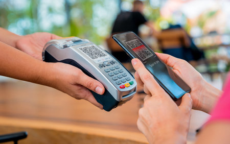 Woman using contactless payment by mobile phone with QR code at cafeの写真素材