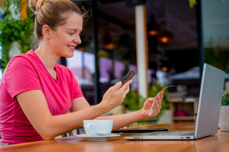 Woman using contactless payment by mobile phone with QR code at cafeの写真素材