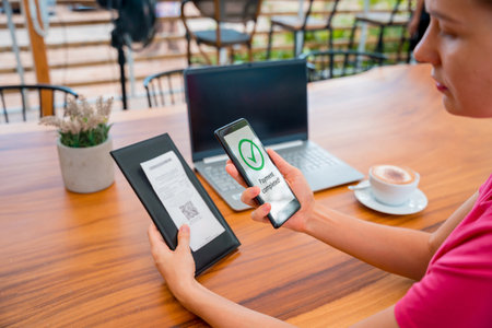 Woman using contactless payment by mobile phone with QR code at cafeの写真素材