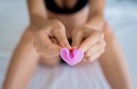 Young beautiful woman at home holding a menstrual cup in her handsの写真素材