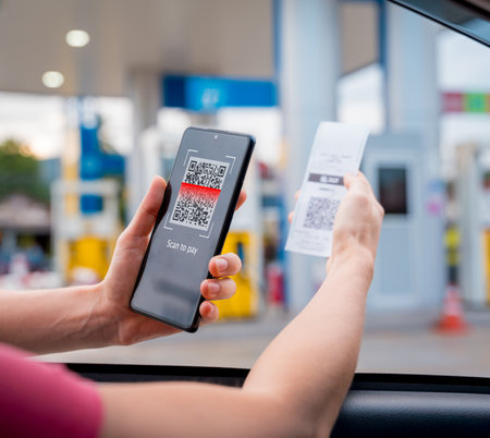 Woman using contactless payment by mobile phone with QR code at car filling stationの写真素材