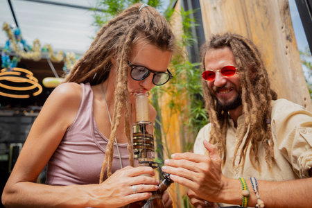Hippie style couple smoking medical marijuana using a bongの写真素材