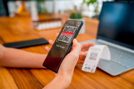 Woman using contactless payment by mobile phone with QR code at cafeの写真素材