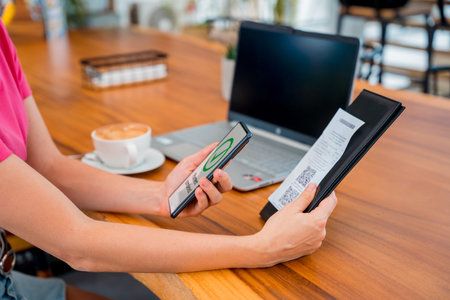 Woman using contactless payment by mobile phone with QR code at cafe