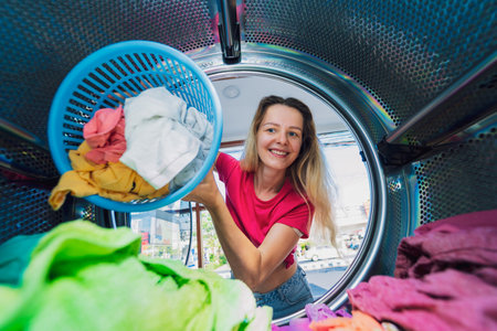 Young beautiful woman washes and dries clothes in the laundryの写真素材