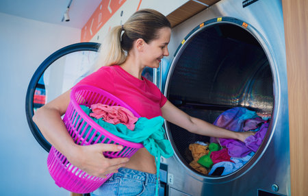 Young beautiful woman washes and dries clothes in the laundryの写真素材