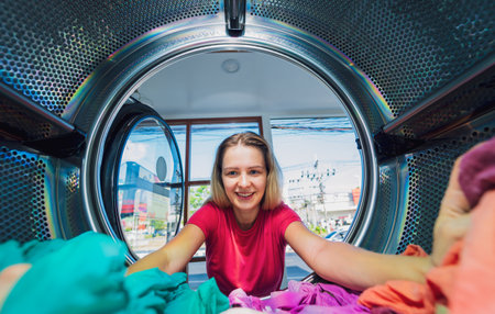 Young beautiful woman washes and dries clothes in the laundryの写真素材