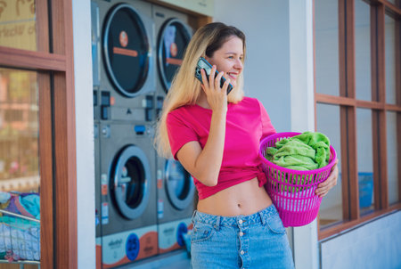 Young beautiful woman talking by the phone in the laundryの写真素材