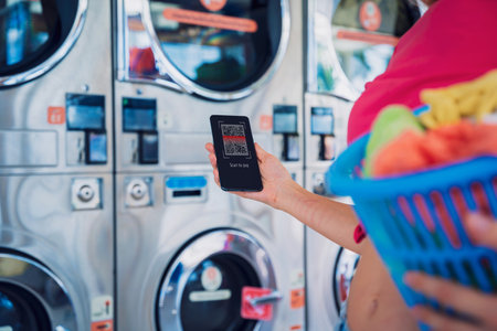Young woman pays for laundry service using phone and banking applicationの写真素材