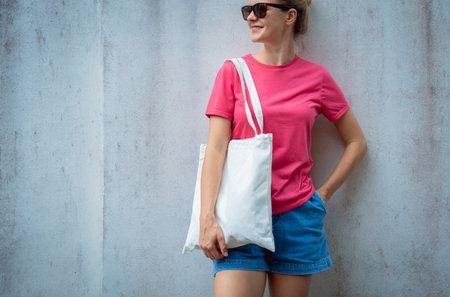Female model wearing pink blank t-shirt on the background of an gray wall.の写真素材