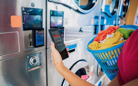 Young woman pays for laundry service using phone and banking applicationの写真素材
