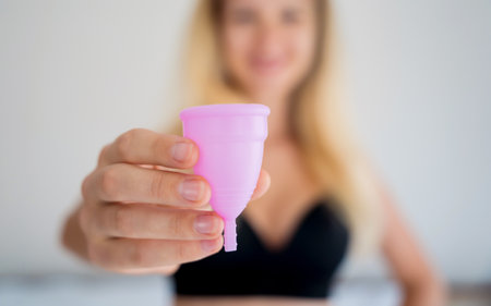 Young beautiful woman at home holding a menstrual cup in her handsの写真素材