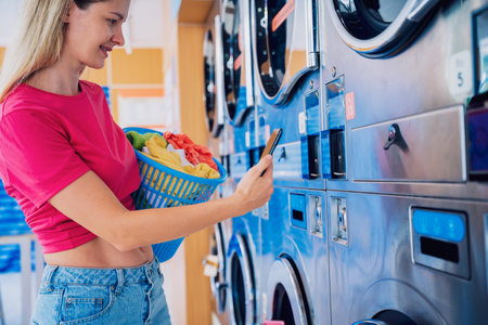 Young woman pays for laundry service using phone and banking applicationの写真素材