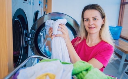 Young beautiful woman washes and dries clothes in the laundryの写真素材