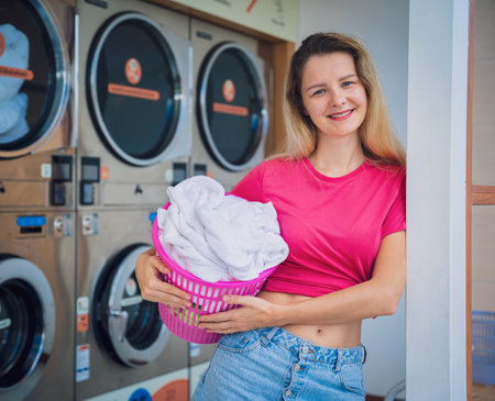 Young beautiful woman washes and dries clothes in the laundryの写真素材