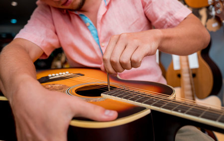 Young musician tuning a classical guitar in a guitar shop