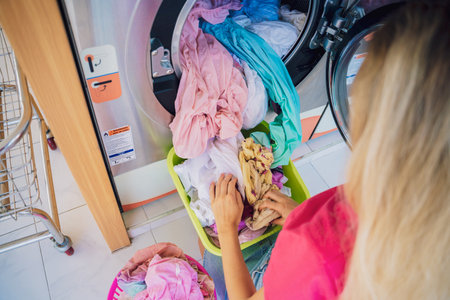 Young beautiful woman washes and dries clothes in the laundryの写真素材