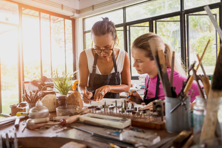 Teacher jeweler and student make jewelry in workshopの写真素材