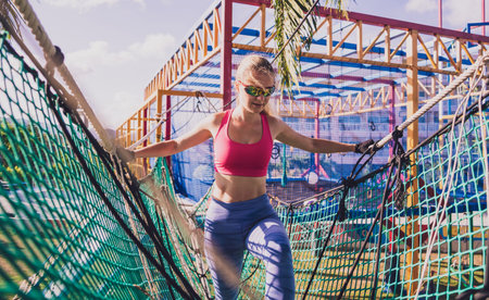 Athletic young woman working out at the rope training camp.