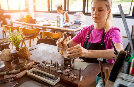 Young female jeweler making jewelry in workshopの写真素材