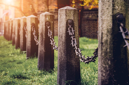 Old stone posts with chains on a background of green grassの写真素材