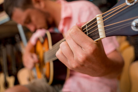Young musician testing classical guitar in a guitar shop