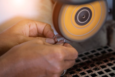 Teacher jeweler and student polishing jewelry in workshopの写真素材