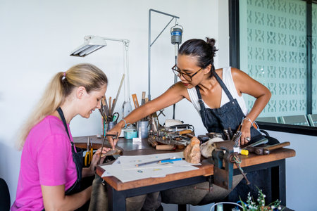 Teacher jeweler and student make jewelry in workshopの写真素材