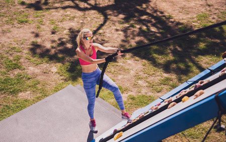 Athletic young woman working out and climbing a ropes at the rope training camp.