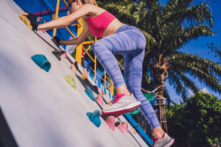 Athletic young woman working out and climbing at the artificial rock in training camp.の写真素材